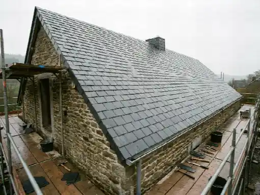 Versant fraîchement couvert d'ardoises naturelles sur une maison en pierre